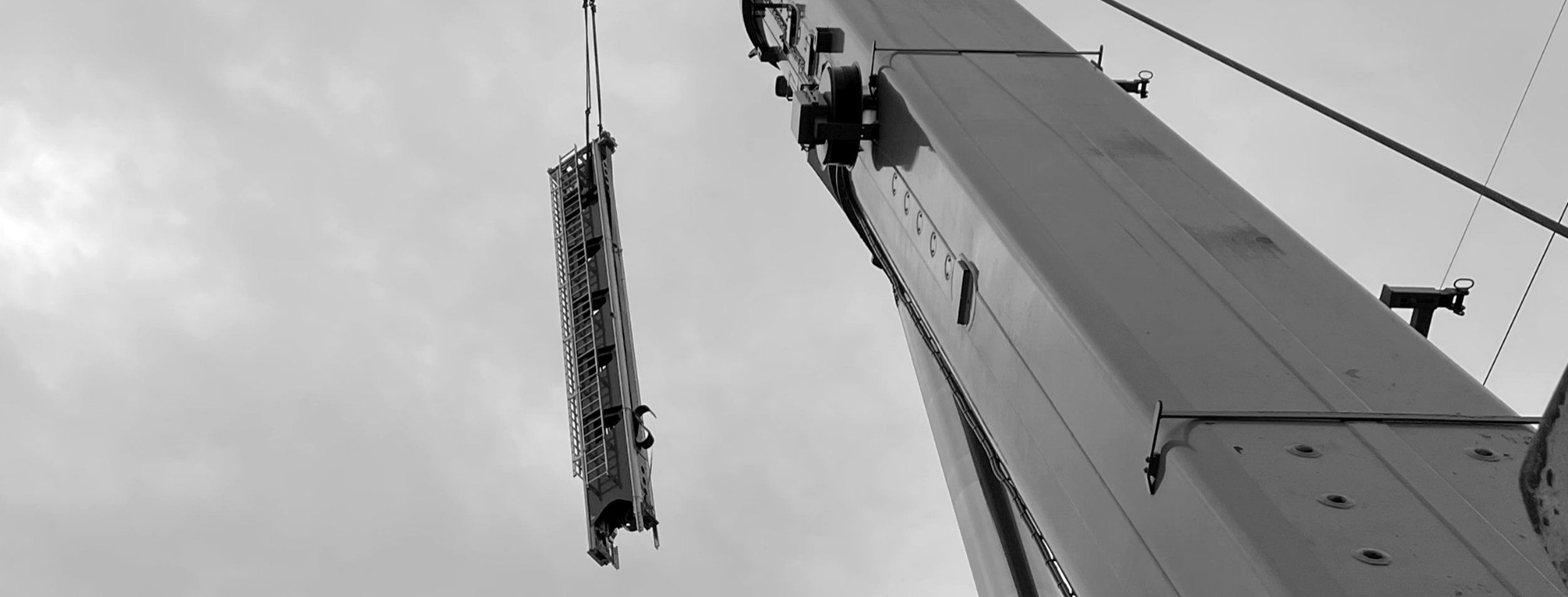 Grúa elevando un tramo de mástil de un transelevador sobre las instalaciones
