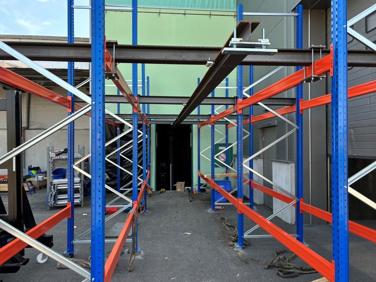 Estructura de estantería con una viga de acero delante de la puerta de la nave durante el montaje
